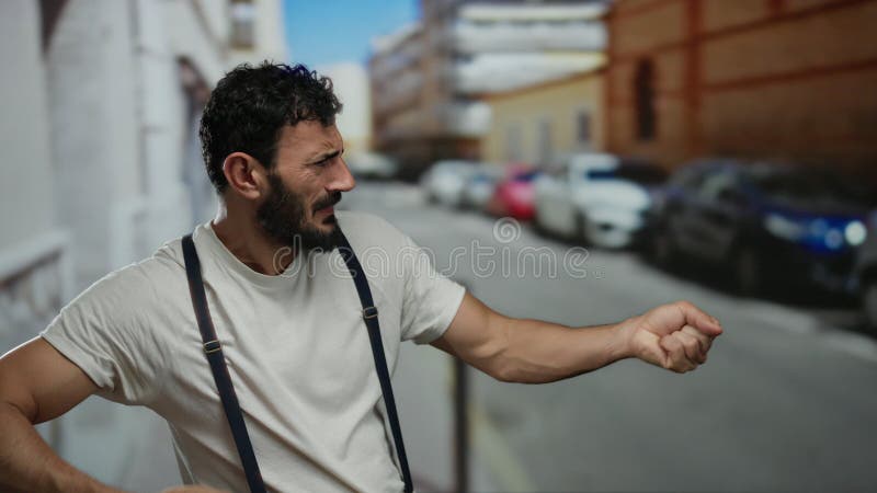 Hispanic man with beard mimics pulling a rope energetically on an urban street with blurred background during daytime royalty free stock image