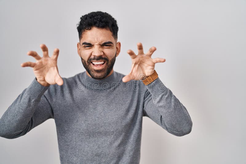 Hispanic man with beard standing over white background smiling funny doing claw gesture as cat, aggressive and expression
