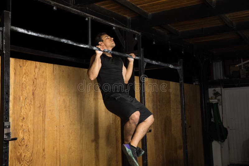 Hispanic man doing chin-ups at the gym