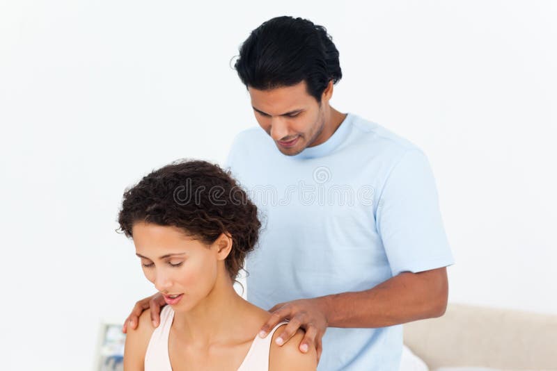 Hispanic man doing a massage to his beautiful wife on their bed