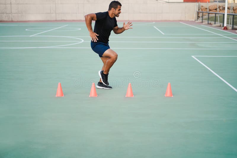 Hispanic Man Doing Speed and Agility Cone Drills Workout Session Outdoors Focus on Man Face