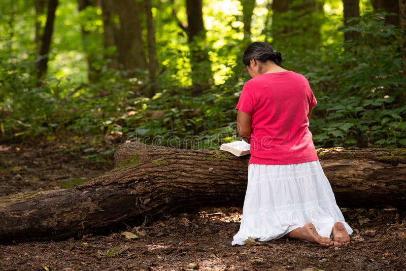 Woman in Forest Preserve with Bible Kneeling in Prayer