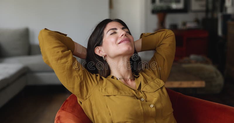 Hispanic woman put hands behind head resting on comfortable armchair stock footage