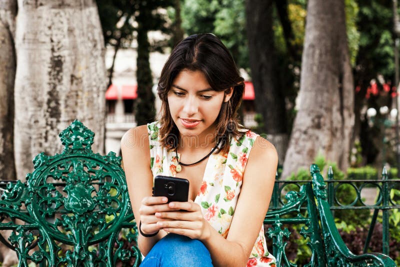 Hispanic woman texting with her phone, Mexican beautiful woman in Mexico stock photography