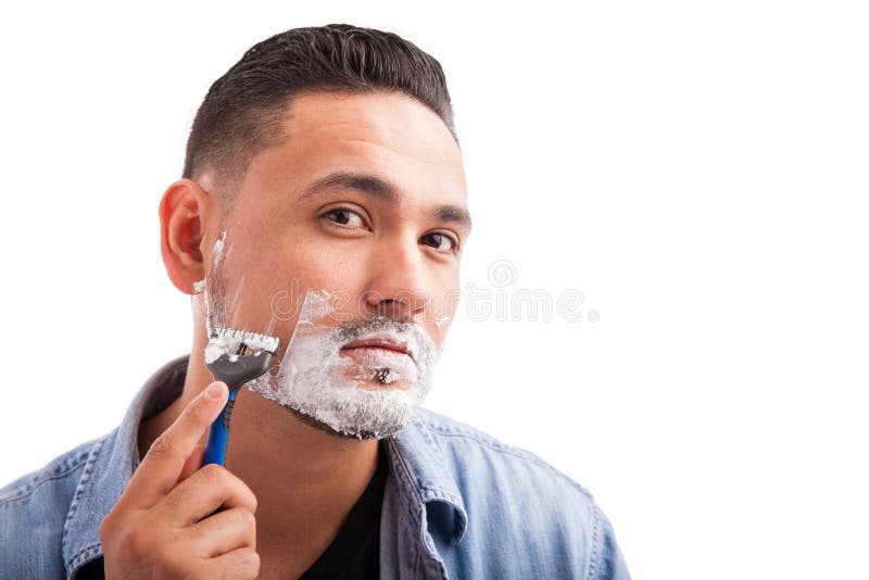 Hispanic young man shaving his beard stock photography