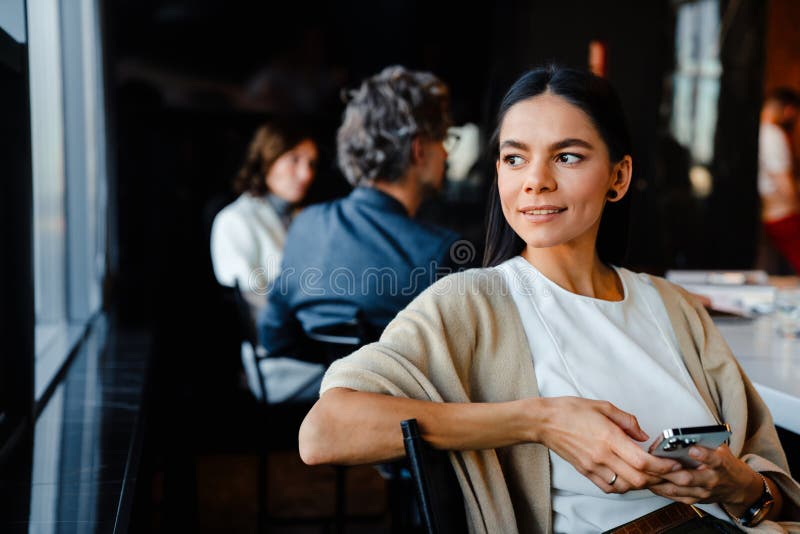 Hispanische junge Frau lächelt und benutzt Handy während Offline-Sitzung lizenzfreies stockfoto