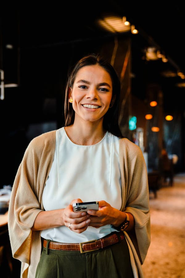 Hispanische junge Frau lächelt und benutzt Handy während Offline-Sitzung lizenzfreie stockfotos
