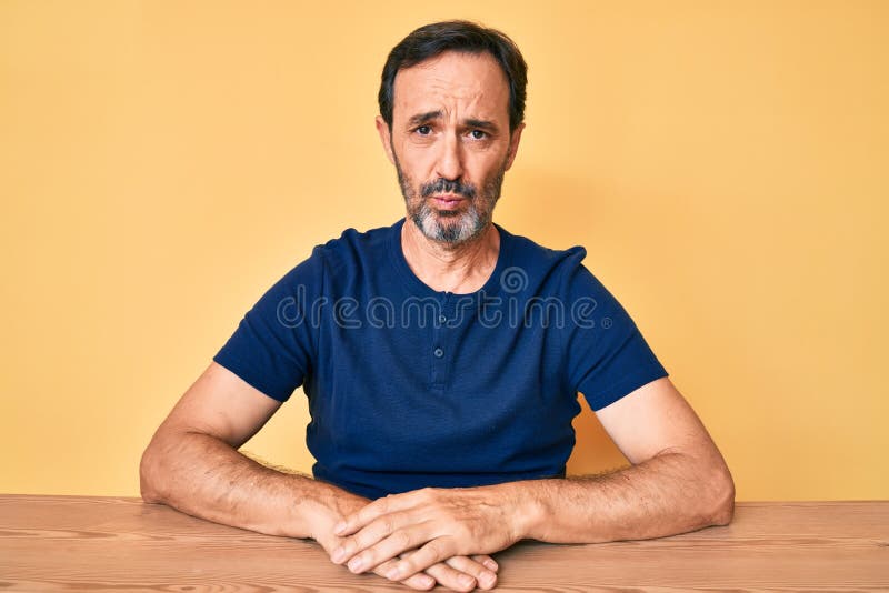 Hispano de mediana edad con ropa casual sentado en la mesa deprimido y preocupado por angustia llorando enojado y asustado foto de archivo libre de regalías