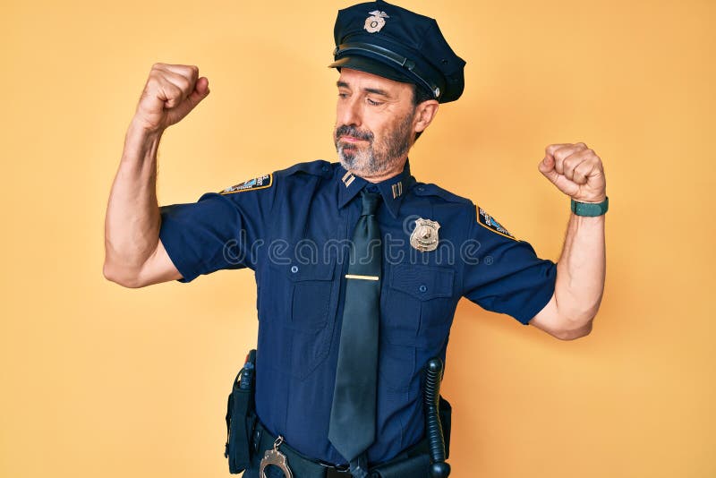 Hispano de mediana edad con uniforme de policía mostrando los músculos de los brazos sonriendo orgulloso fotos de archivo