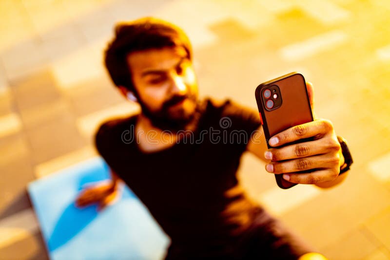 Hispano latino con camiseta de algodón negro con un earpón calentándose al aire libre al atardecer luces doradas fotografía de archivo libre de regalías