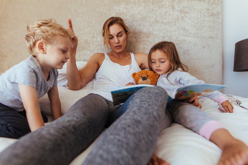Histoire pour endormir de lecture de mère aux enfants image stock Histoire pour endormir de lecture de mère aux enfants image stock