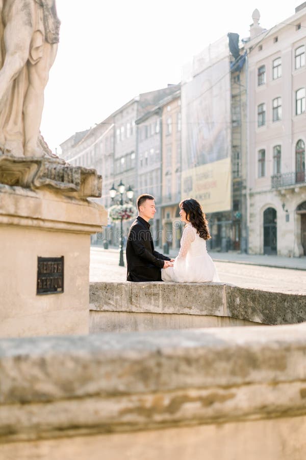 Historia de amor o sesión de bodas de una joven pareja asiática en el centro de la ciudad vieja, sentada en la fuente antigua, m foto de archivo libre de regalías Historia de amor o sesión de bodas de una joven pareja asiática en el centro de la ciudad vieja, sentada en la fuente antigua, m foto de archivo libre de regalías