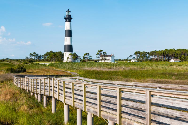 Historic Bodie Island lighthouse, surrounding buildings and wooden walkway to observation point. It is located south of Nags Head on the Outer Banks in North Carolina. Historic Bodie Island lighthouse, surrounding buildings and wooden walkway to observation point. It is located south of Nags Head on the Outer Banks in North Carolina.