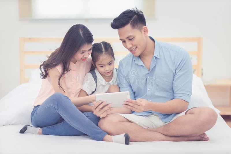 Historieta de observación asiática del padre y de la madre con la hija foto de archivo libre de regalías Historieta de observación asiática del padre y de la madre con la hija foto de archivo libre de regalías