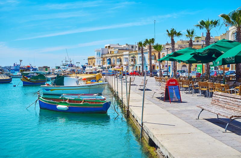 historiska stora byggnader och förtöjde maltesiska luzzufartyg, Marsaxlokk arkivfoto historiska stora byggnader och förtöjde maltesiska luzzufartyg, Marsaxlokk arkivfoto