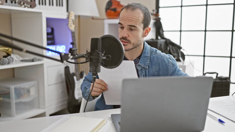 Hiszpański mężczyzna z brodą nagrywającą podcast w nowoczesnym studio muzycznym wnętrz zdjęcia royalty free