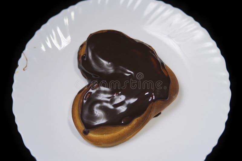 Hjärta-formade den täckte bullechokladen, ligger på en vit platta royaltyfria foton Hjärta-formade den täckte bullechokladen, ligger på en vit platta royaltyfria foton