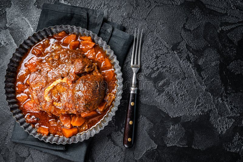 Hjärtat kött med ben osso buco i tomatsås kalvkött med kursiskt kött ossobuco. svart bakgrund. översta vyn. kopieringsutrymme.