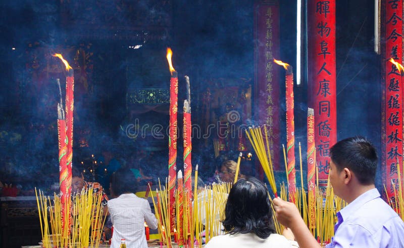 HO CHI MINH CITY VIETNAM - JANUARI 5 2015: Buddistiska troenden tänder rökelsepinnar på relikskrin i kinesisk buddistisk tempel arkivbild HO CHI MINH CITY VIETNAM - JANUARI 5 2015: Buddistiska troenden tänder rökelsepinnar på relikskrin i kinesisk buddistisk tempel arkivbild