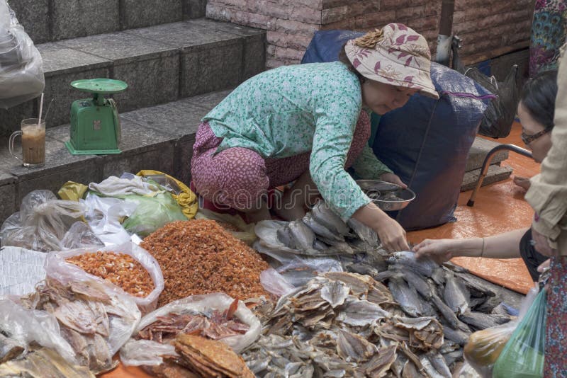 HO CHI MINH CITY,VIETNAM-NOV 5TH: A woman street vendor assisting her customers on November 5th 2013. Many street markets open. For business early in the royalty free stock image HO CHI MINH CITY,VIETNAM-NOV 5TH: A woman street vendor assisting her customers on November 5th 2013. Many street markets open. For business early in the royalty free stock image