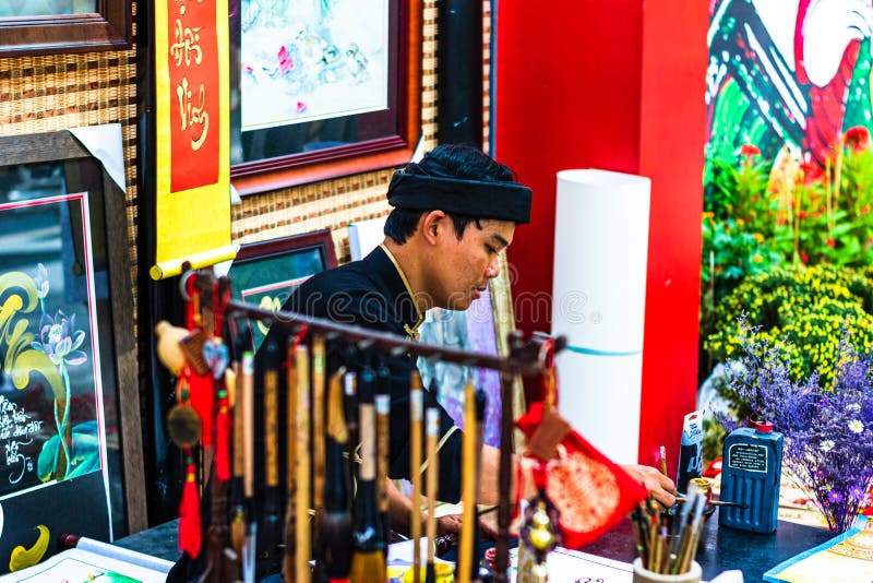 Ho Chi Minh City, Vietnam – 2019. Vietnamese man in ao dai, write Chinese writing or calligraphy at spring fair in Ho Chi Minh, royalty free stock photography Ho Chi Minh City, Vietnam – 2019. Vietnamese man in ao dai, write Chinese writing or calligraphy at spring fair in Ho Chi Minh, royalty free stock photography
