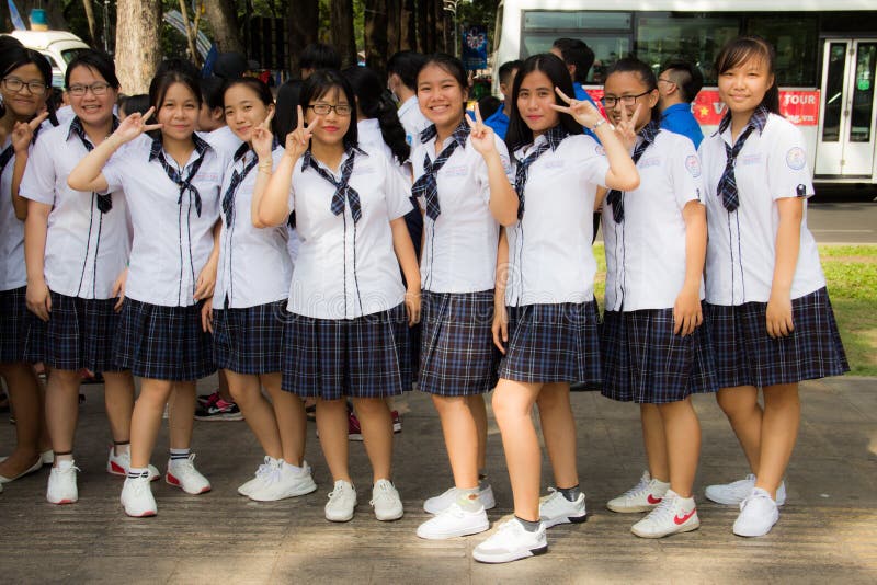 Ho Chi Minh stad, Vietnam, 21 03 2018 - Nio unga vietnamesiska flickor som satying i linje i skolalikformig på gatan royaltyfri fotografi Ho Chi Minh stad, Vietnam, 21 03 2018 - Nio unga vietnamesiska flickor som satying i linje i skolalikformig på gatan royaltyfri fotografi