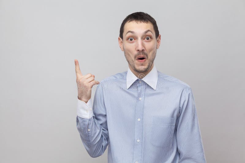 Ho un'idea Ritratto dell'uomo d'affari bello sorpreso felice della setola nella condizione blu classica della camicia con il dito fotografia stock libera da diritti Ho un'idea Ritratto dell'uomo d'affari bello sorpreso felice della setola nella condizione blu classica della camicia con il dito fotografia stock libera da diritti