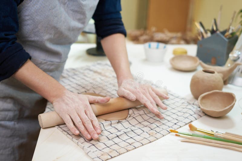 Mestre feminino trabalhando com argila crua na sala de cerâmica