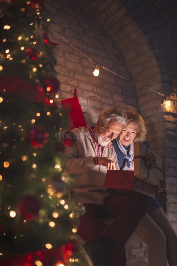 Hochrangiges Ehepaar mit leuchtendem Geschenk an Heiligabend stockfoto