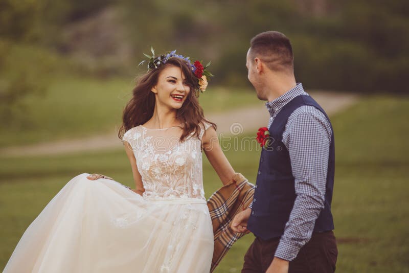hochzeit Braut und Bräutigamhändchenhalten und -weg auf dem grünen Feld stockbild hochzeit Braut und Bräutigamhändchenhalten und -weg auf dem grünen Feld stockbild