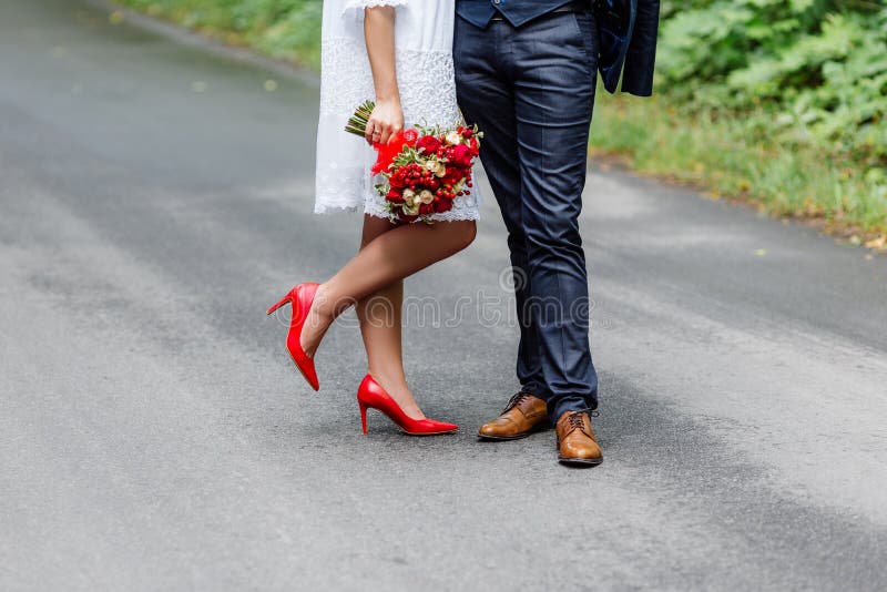 Hochzeitsdetails: stilvolle rote und braune Schuhe der Braut und des Bräutigams Jungvermählten, die vor einander stehen Brautblum stockfotos Hochzeitsdetails: stilvolle rote und braune Schuhe der Braut und des Bräutigams Jungvermählten, die vor einander stehen Brautblum stockfotos