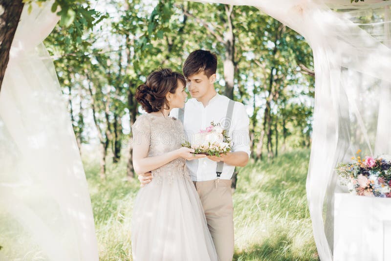 Hochzeitspaare auf Natur die Braut und der Bräutigam mit Kuchen an der Hochzeit lizenzfreie stockfotografie Hochzeitspaare auf Natur die Braut und der Bräutigam mit Kuchen an der Hochzeit lizenzfreie stockfotografie