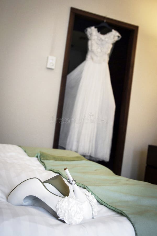 White wedding sandals in detail with wedding dress in background. White wedding sandals in detail with wedding dress in background