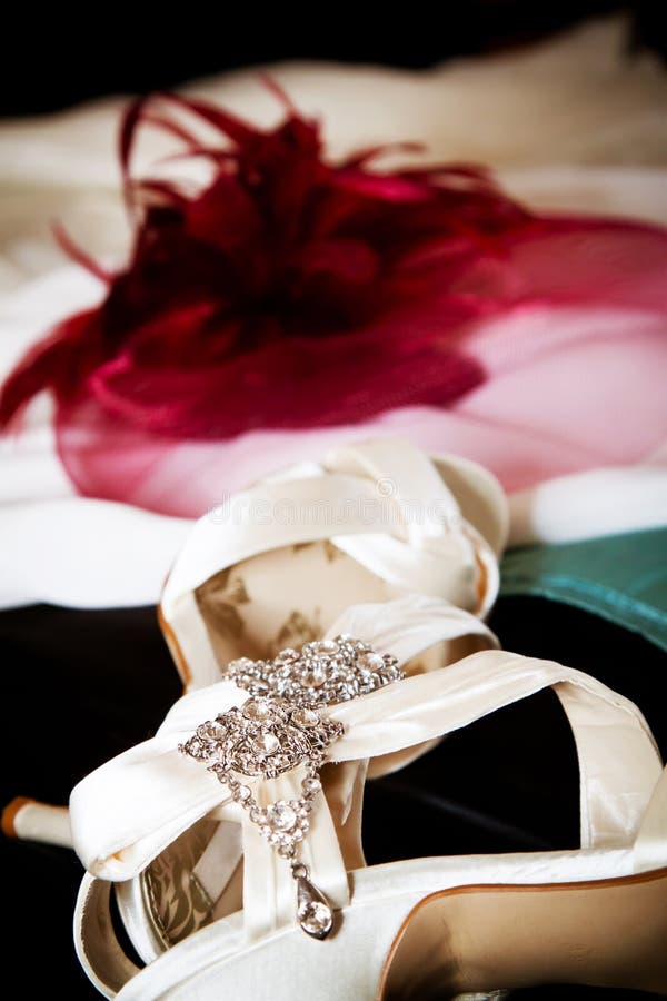 Wedding preparation: the bride's gown, shoes and hat ready to be worn. Shallow depth of field with focus on jewel on the sandals. Wedding preparation: the bride's gown, shoes and hat ready to be worn. Shallow depth of field with focus on jewel on the sandals.