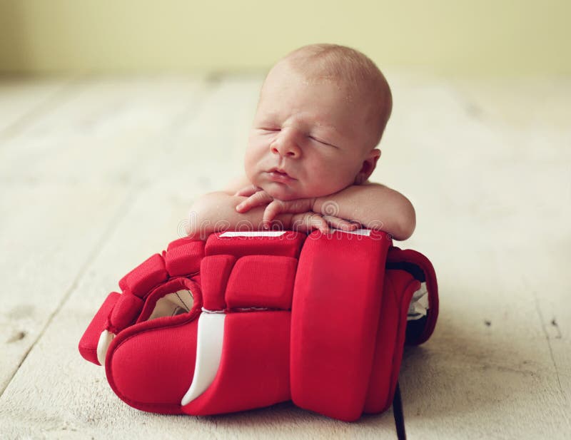 Carino neonato bambino a dormire su un guanto di hockey.