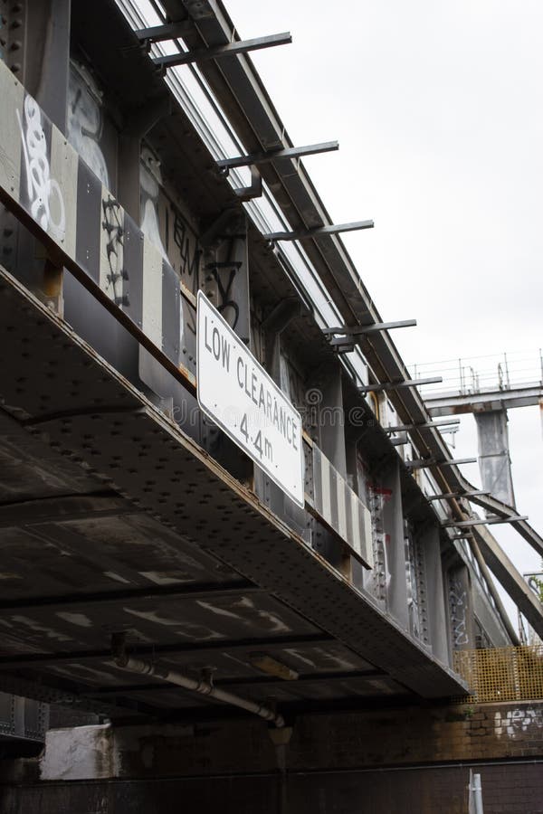 An angled shot of a sign on the side of an overpass indicating a low clearance of 4.4 mters. An angled shot of a sign on the side of an overpass indicating a low clearance of 4.4 mters