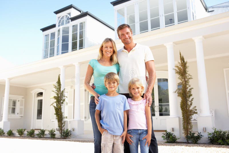 Young Family Standing Outside Dream Home Smiling At Camera. Young Family Standing Outside Dream Home Smiling At Camera