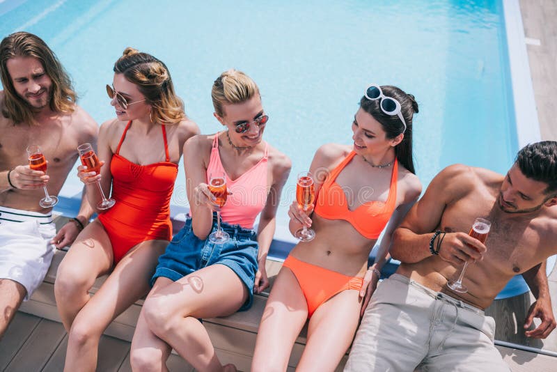 hoge hoekmening van glimlachende jonge vrienden die champagne en het rusten drinken stock foto hoge hoekmening van glimlachende jonge vrienden die champagne en het rusten drinken stock foto