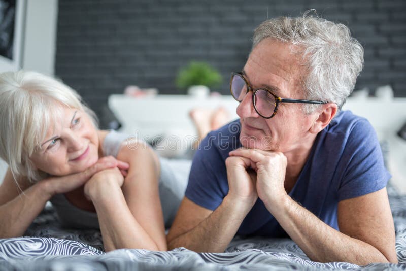 Hoger gelukkig paar die op bed liggen die elkaar bekijken stock afbeelding Hoger gelukkig paar die op bed liggen die elkaar bekijken stock afbeelding
