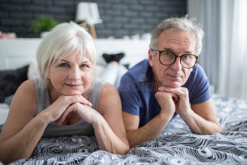 Hoger paar die op bed propping hoofden liggen op handen royalty-vrije stock foto Hoger paar die op bed propping hoofden liggen op handen royalty-vrije stock foto