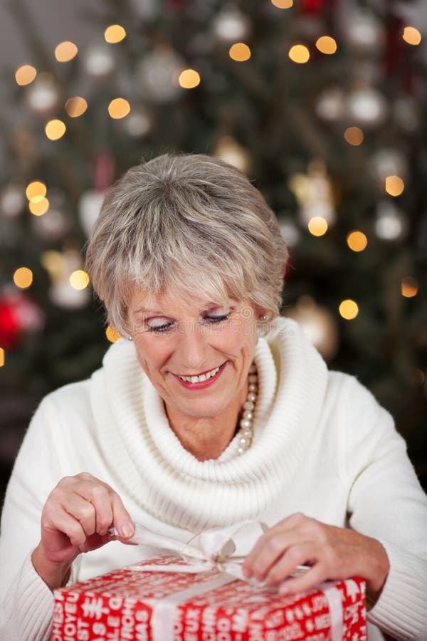Hogere dame die haar Kerstmisgift openen royalty-vrije stock foto Hogere dame die haar Kerstmisgift openen royalty-vrije stock foto