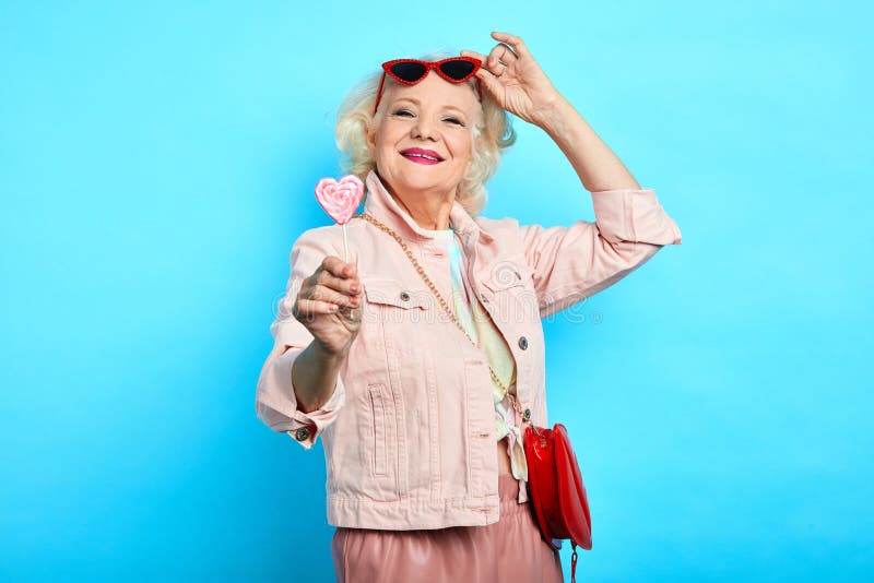 Hogere dame die van het glamour de ontzagwekkende blonde zonnebril opstijgen, terwijl het eten van lolly royalty-vrije stock foto Hogere dame die van het glamour de ontzagwekkende blonde zonnebril opstijgen, terwijl het eten van lolly royalty-vrije stock foto