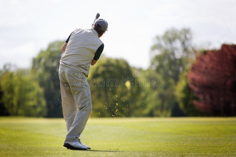 Active senior male golf player swinging golf club to shoot ball on fairway on beautiful golf course. Active senior male golf player swinging golf club to shoot ball on fairway on beautiful golf course.