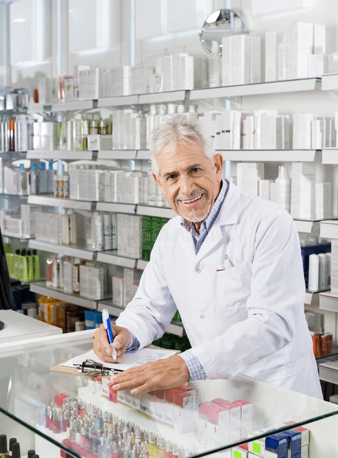 Hogere Mannelijke Chemicus Writing On Clipboard in Apotheek stock foto's Hogere Mannelijke Chemicus Writing On Clipboard in Apotheek stock foto's