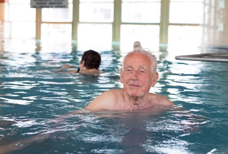 Senior man swimming in indoor pool and enjoying hydrotherapy. Senior man swimming in indoor pool and enjoying hydrotherapy