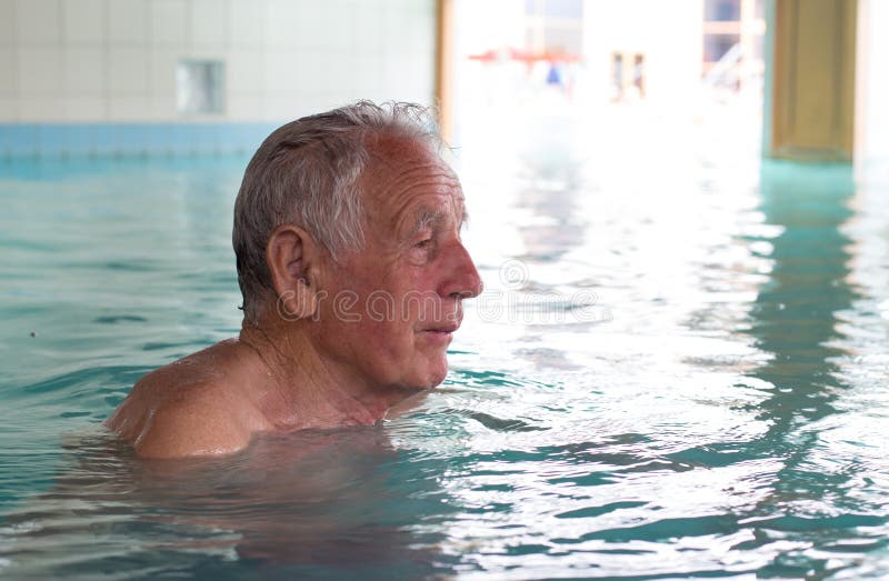 Senior man swimming in indoor pool and enjoying hydrotherapy. Senior man swimming in indoor pool and enjoying hydrotherapy