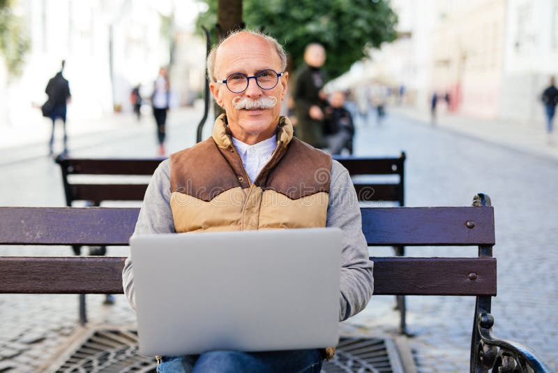 Hogere mens die aan zijn laptop op de bank werken royalty-vrije stock foto's Hogere mens die aan zijn laptop op de bank werken royalty-vrije stock foto's