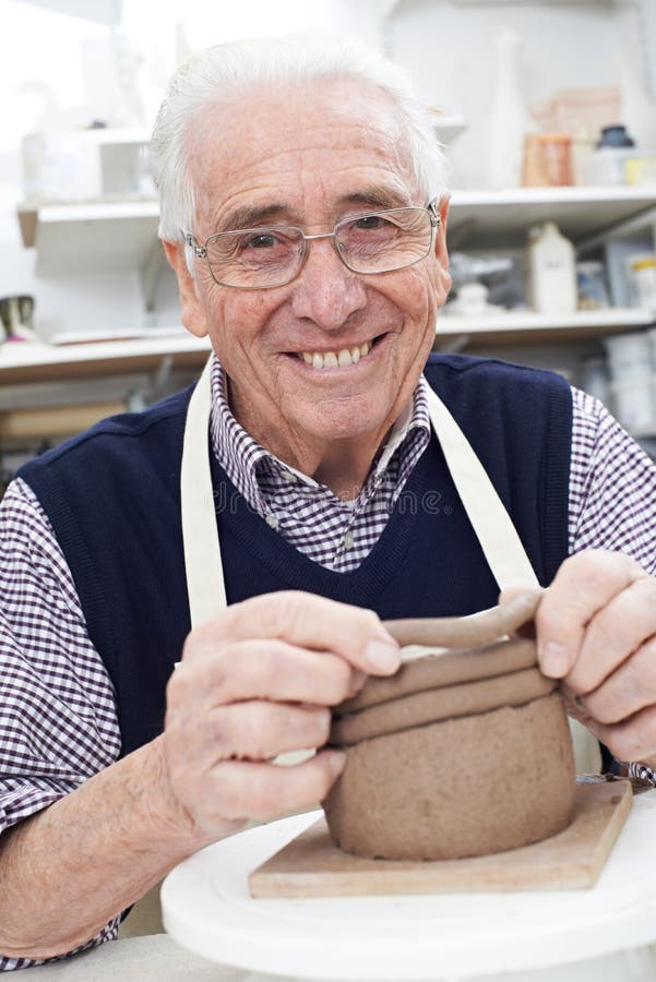 Hogere Mens die Rolpot in Aardewerkstudio maken stock fotografie Hogere Mens die Rolpot in Aardewerkstudio maken stock fotografie