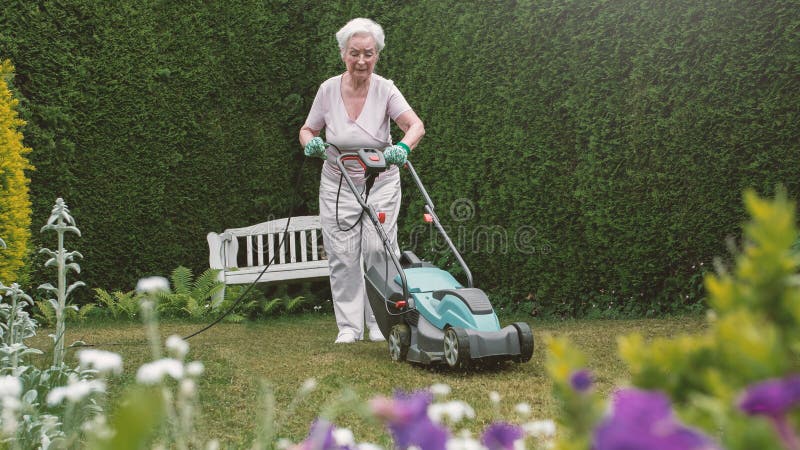 Hogere vrouw die in de tuin met maaimachine werken royalty-vrije stock fotografie Hogere vrouw die in de tuin met maaimachine werken royalty-vrije stock fotografie