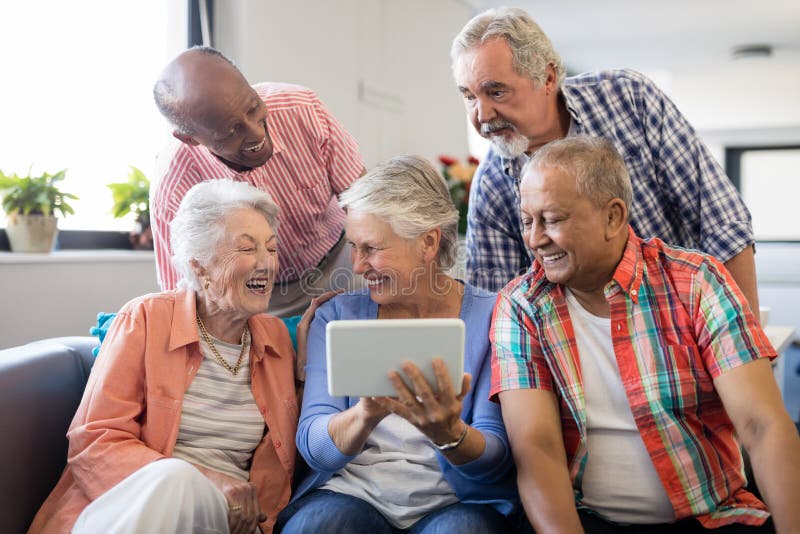 Hogere vrouw die digitale tablet tonen aan vrolijke vrienden stock foto's Hogere vrouw die digitale tablet tonen aan vrolijke vrienden stock foto's
